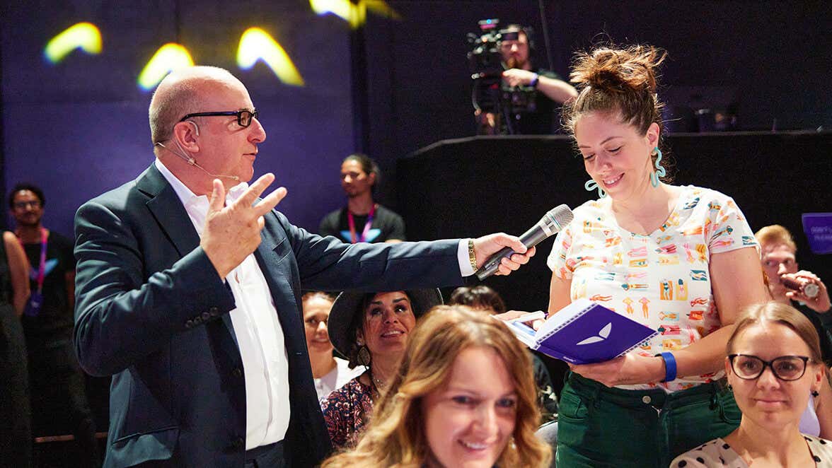 Paul McKenna holding a mic for a participant.