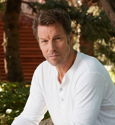 Monty wearing a white long sleeve shirt with a barn-like scenery backdrop