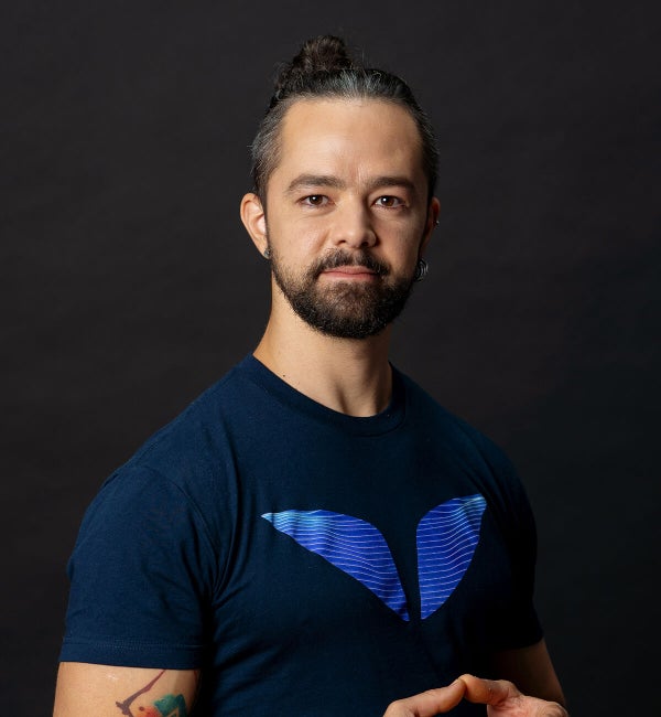 Ronan Diego de Oliveira – Beyond Fasting 4 Ronan in a dark backdrop, arms crossed and smiling.