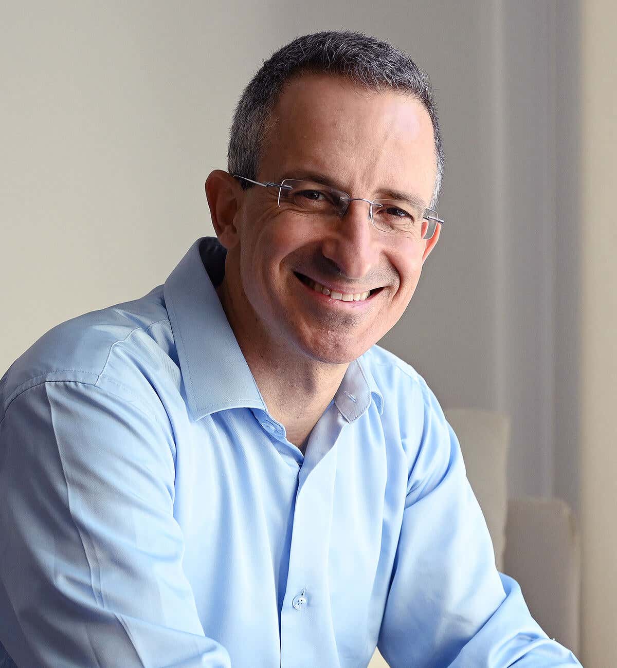 Tal Ben-Shahar wearing a light blue shirt, sitting and smiling