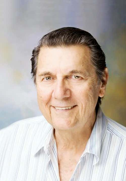 Burt Goldman wearing a vertical striped shirt, front-facing and smiling