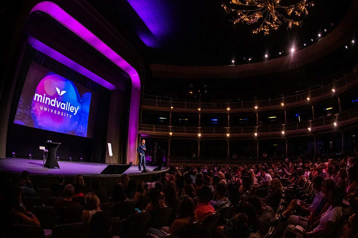 A big group of people hugging each other on the stage of Mindvalley University