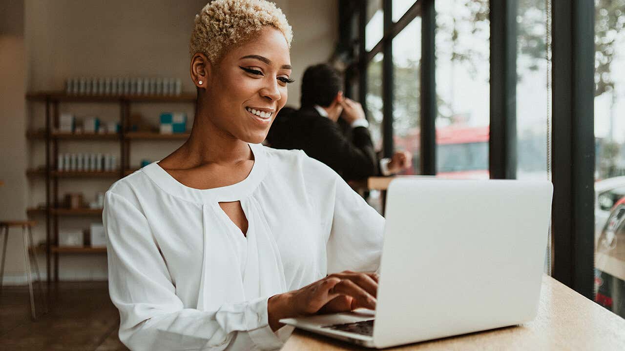 Black woman smiling in front of a laptop