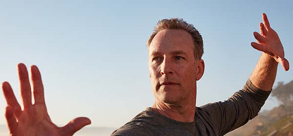 A closeup Lee Holden demonstrating a Qi Gong stance at the beach