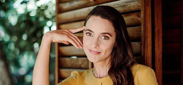 Jennifer Partridge wearing a yellow dress with a wooden door grill backdrop
