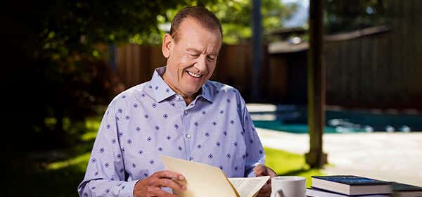 A front profile of Dawson, wearing a patterned light blue shirt, smiling.