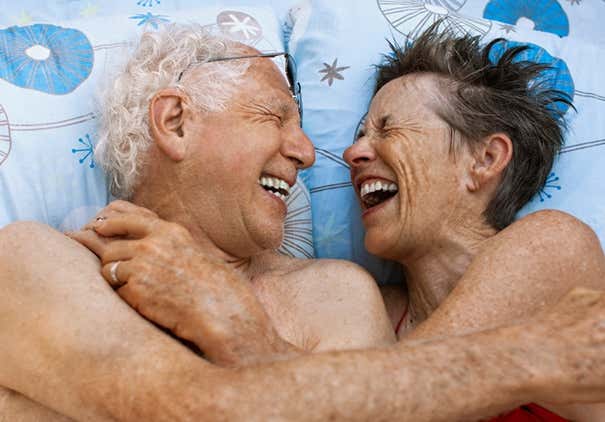 Senior couple laughing in bed