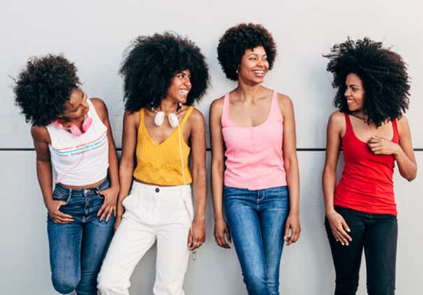 Gorgeous young afro strong women posing besides a grey wall