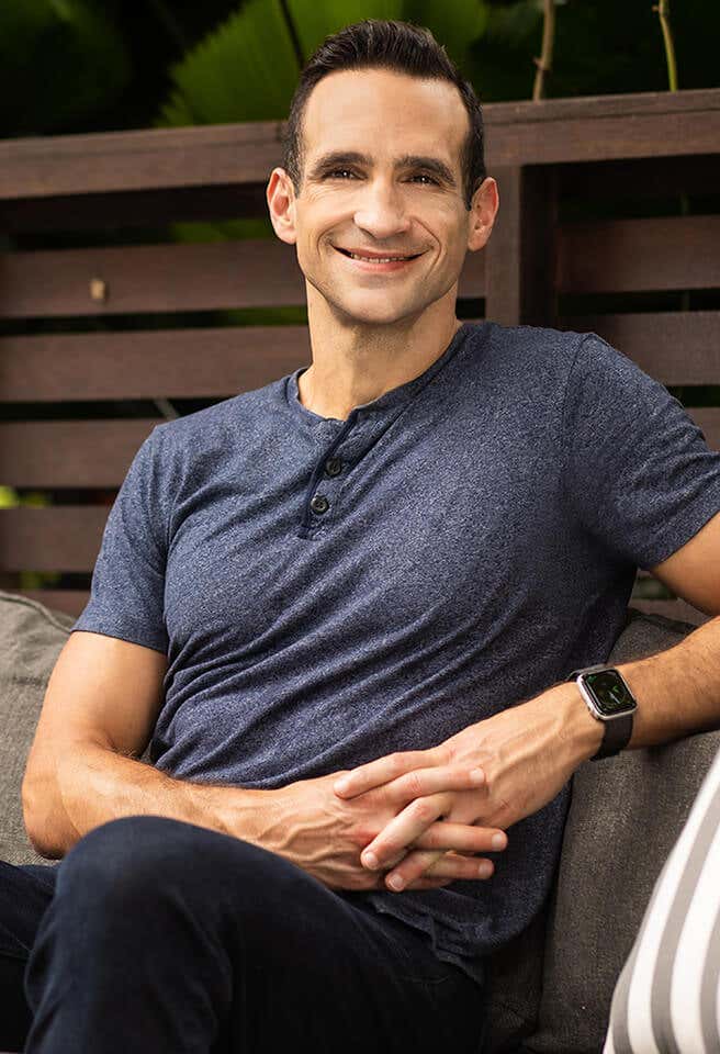 Nir Eyal sitting on a sofa, smiling.