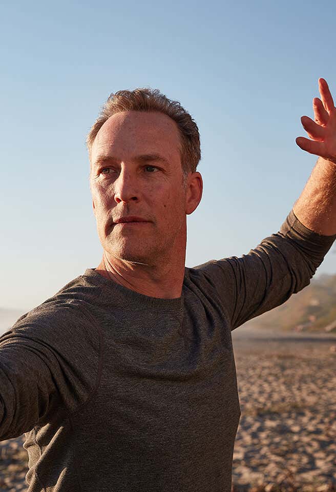 A closeup Lee Holden demonstrating a Qi Gong stance at the beach