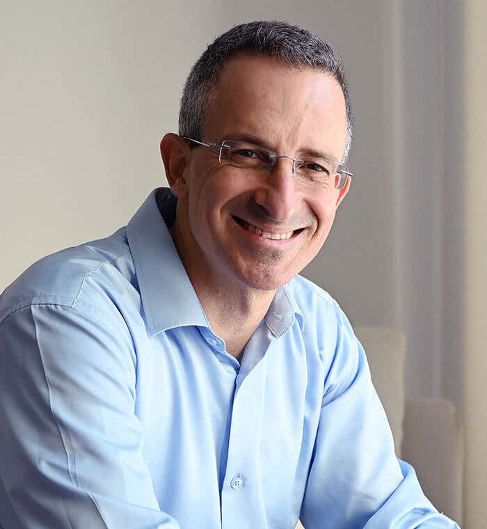 Tal Ben-Shahar wearing a light blue shirt, sitting and smiling
