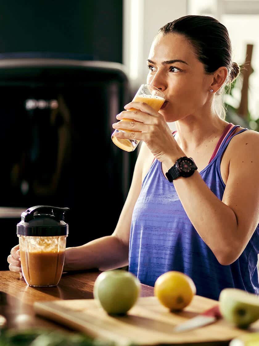 A woman drinking smoothie, looking away from camera